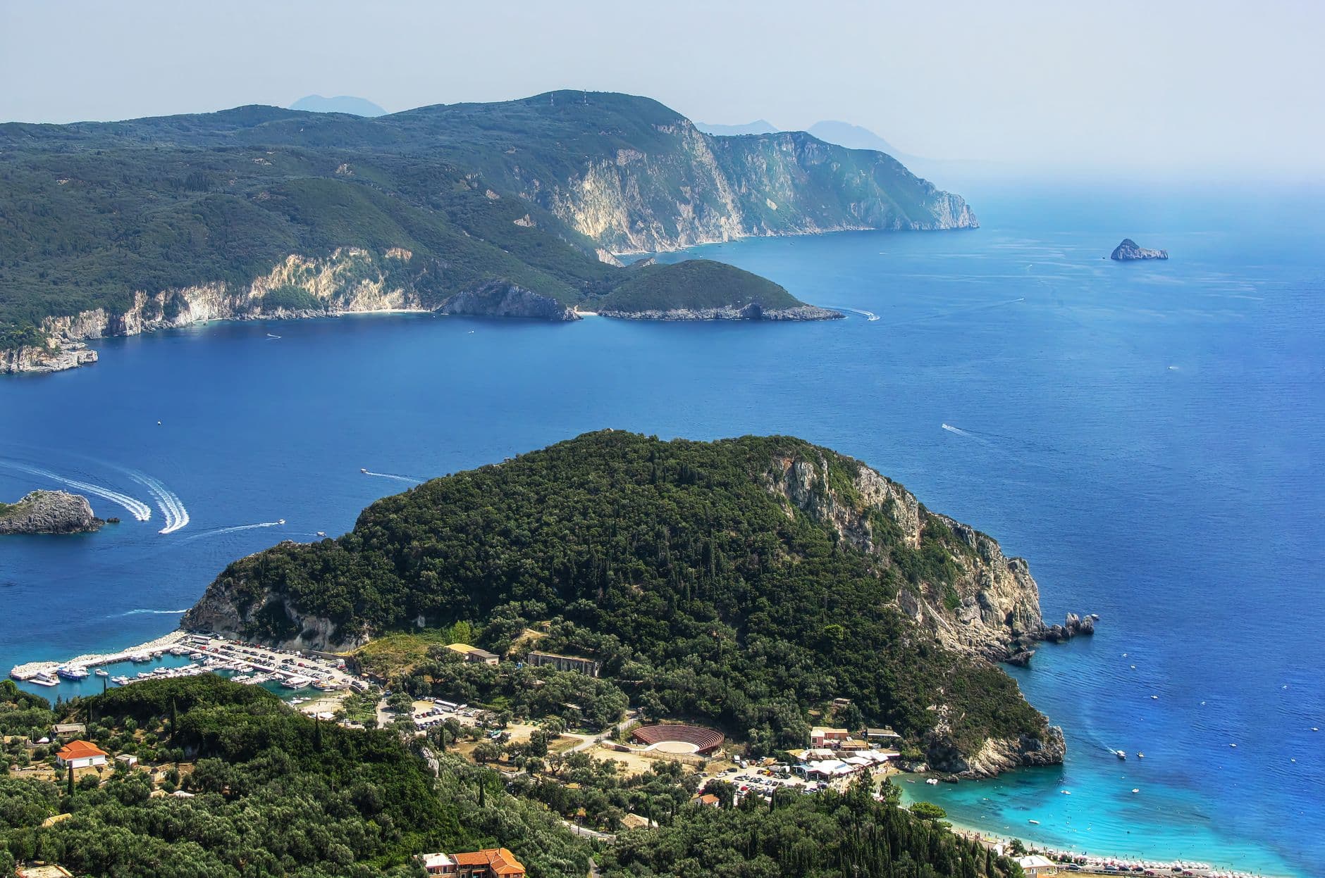 Uitzicht van bovenaf op beboste kapen, een jachthaven en blauw water aan de kust van Corfu