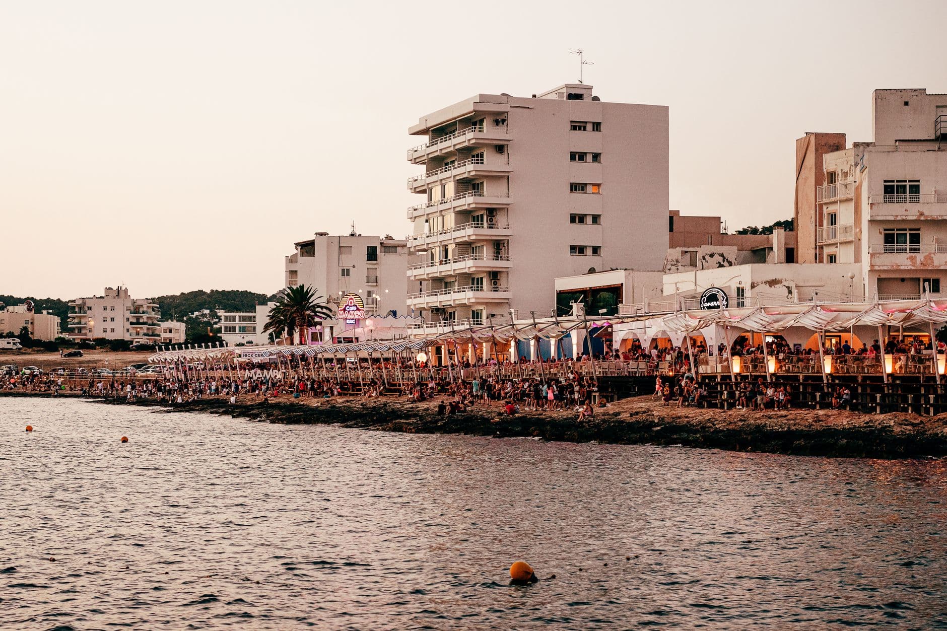 Een drukke boulevard met terrassen aan het water op Ibiza in het avondlicht