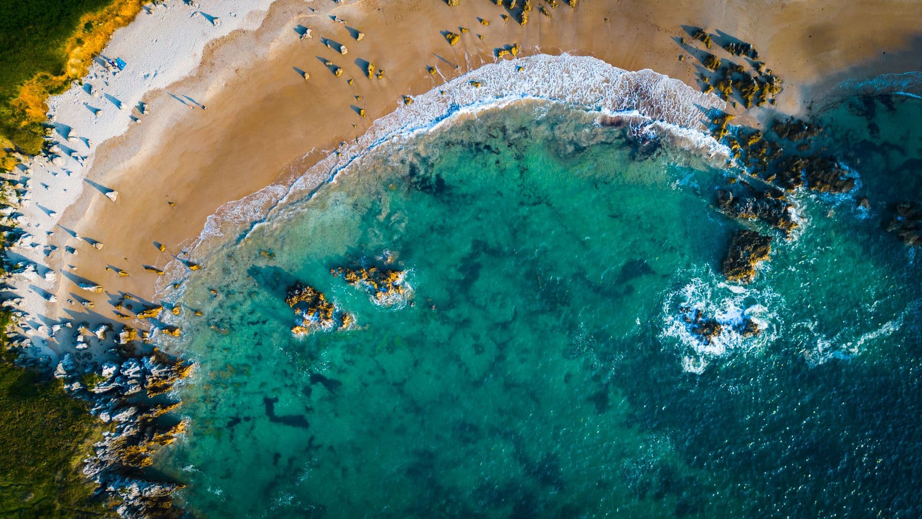 Luchtbeeld van een strand met turquoise water en rotsen aan de Spaanse kust