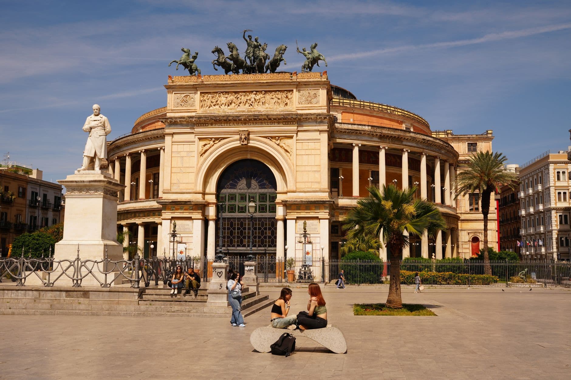 View of Teatro Politeama in Palermo, Sicily with people enjoying a sunny day.