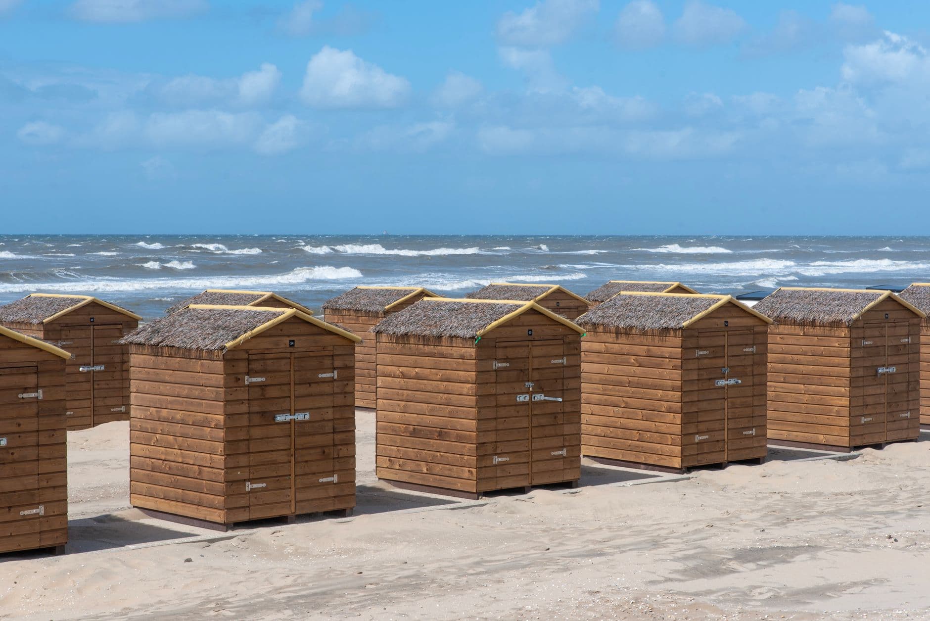 Rustic beach huts aligned along sandy shores at Katwijk aan Zee, Netherlands.