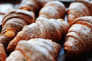 Een dienblad met meerdere croissants bestrooid met poedersuiker