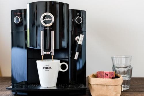 Een zwart stijlvol koffiezetapparaat met een tas onder.